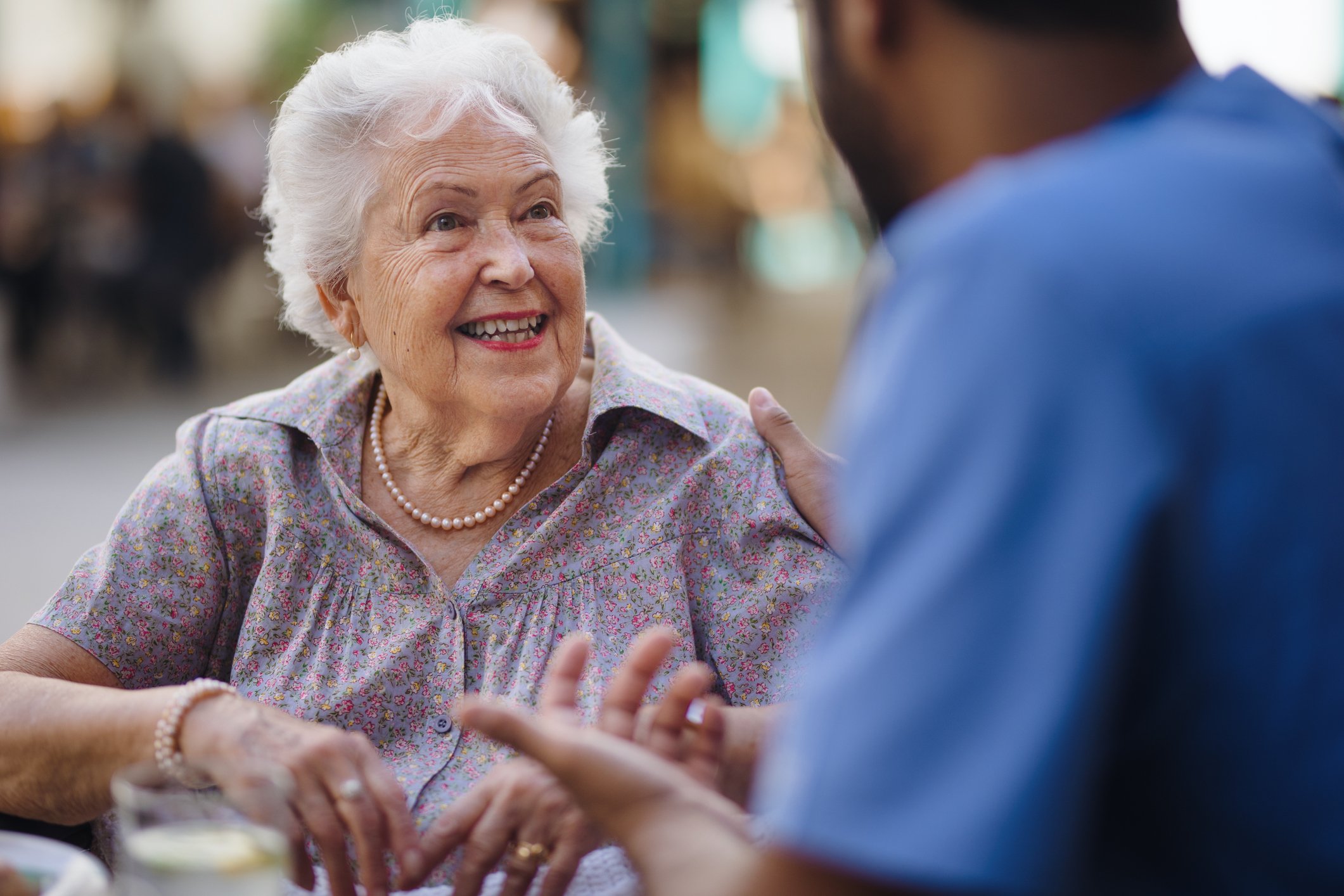 Senior woman smiling & talking to a yound male nurse