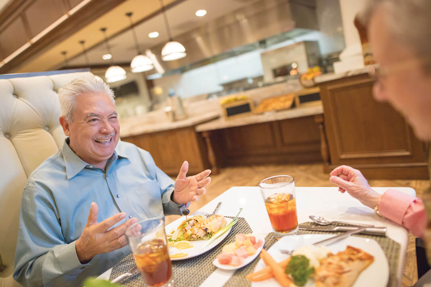 Senior couple seated in a high backed dining booth conversing & smiling