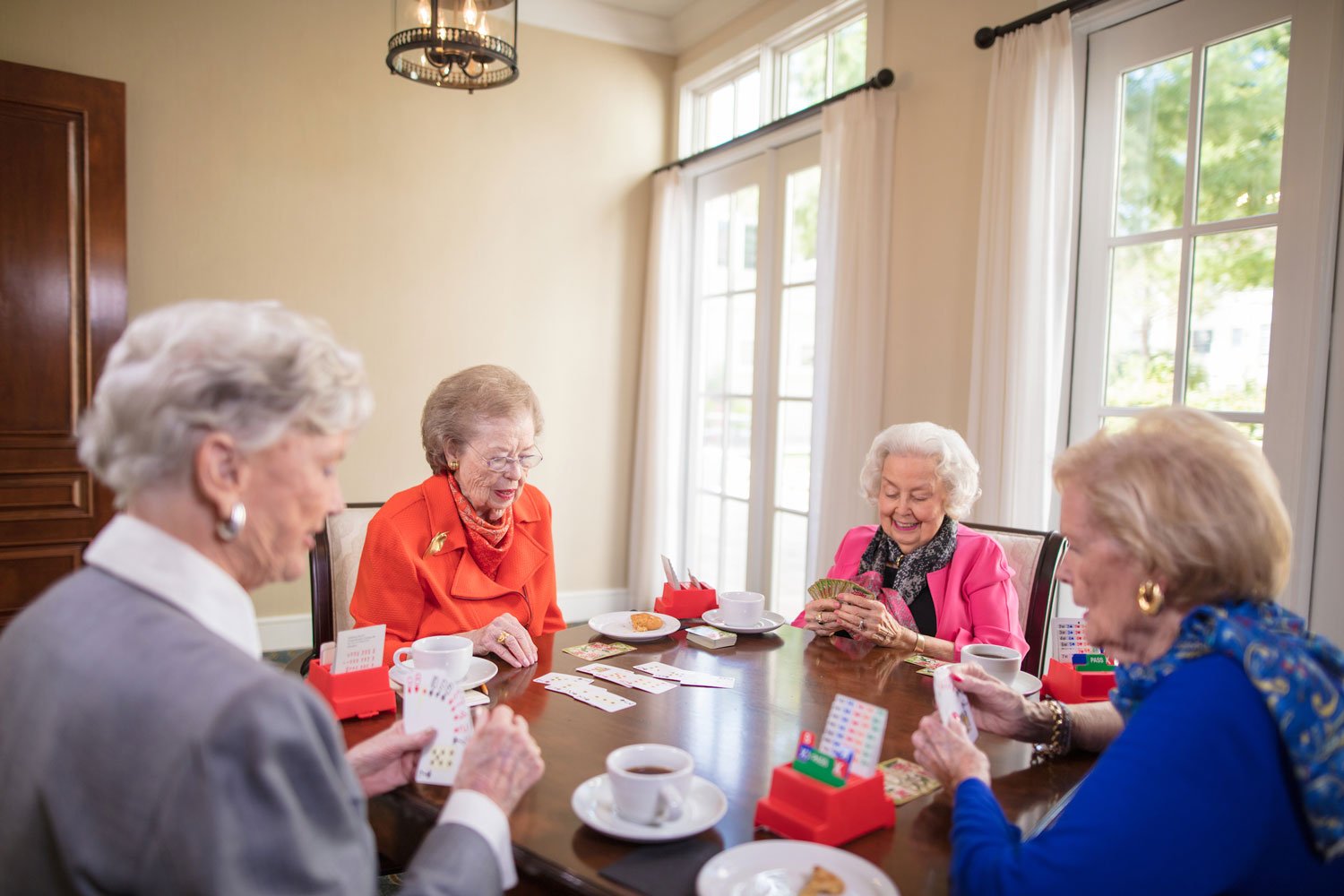 Seniors sitting around a card table playing a card game together