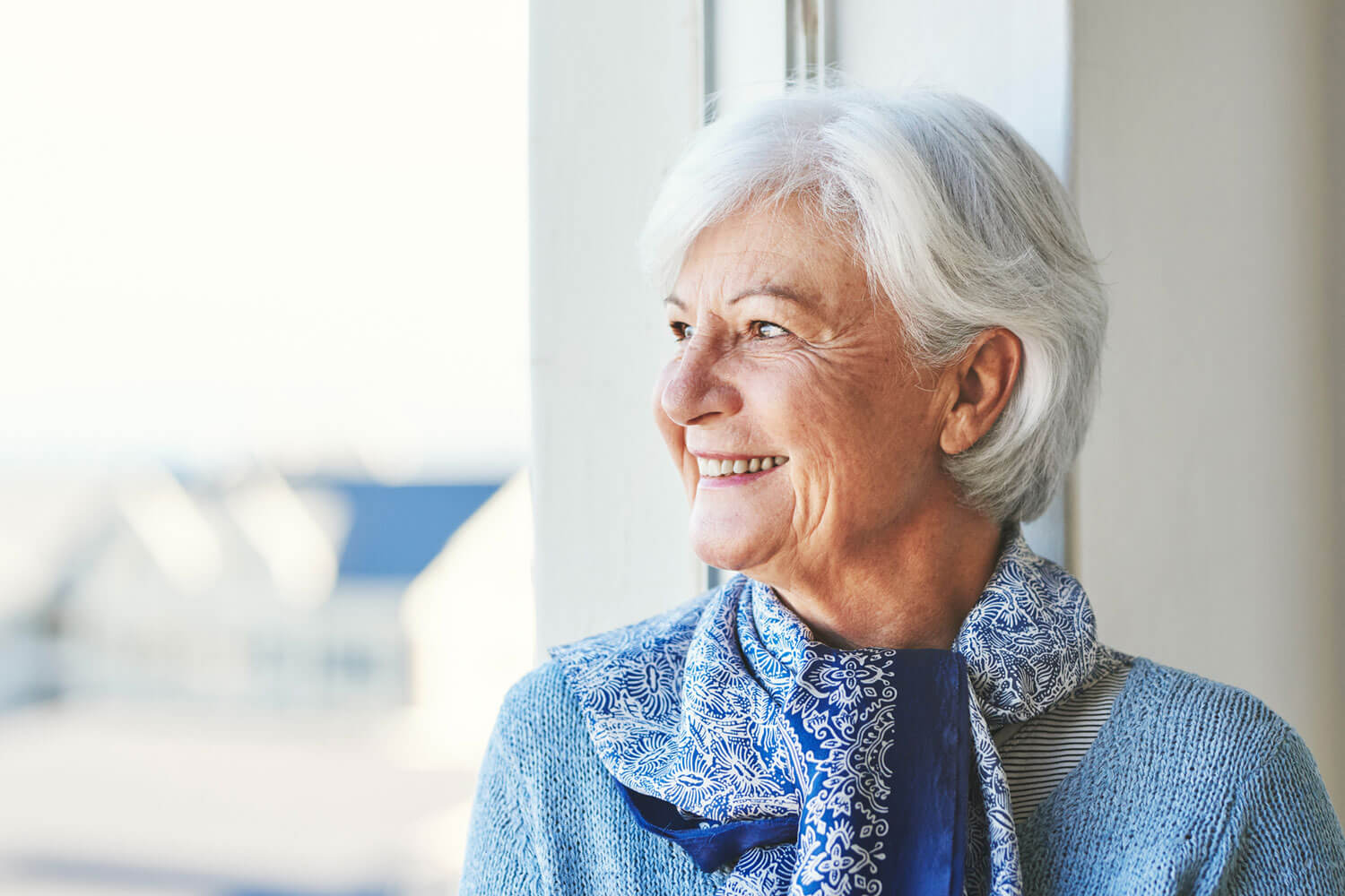 Senior woman smiling while looking out a window