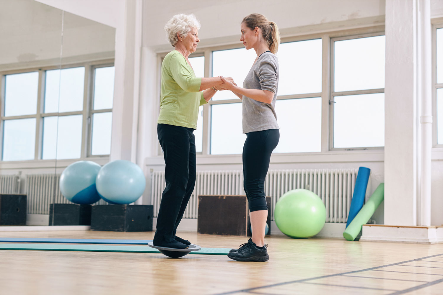 Senior woman using a balance ball with the help of a physical therapist