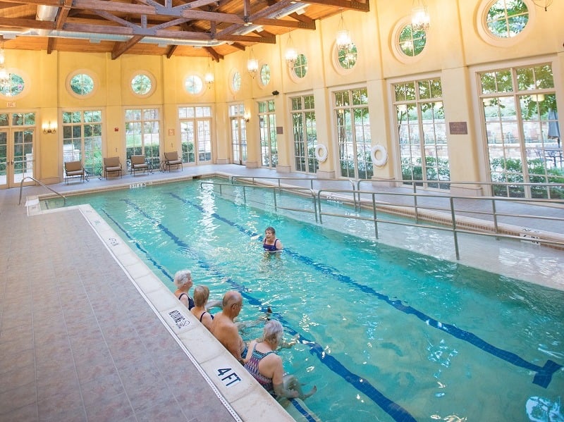 Indoor heated pool with four seniors in it taking part in a water aerobics class