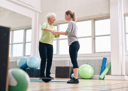 Older adult woman doing physical therapy with therapist in aerobics room